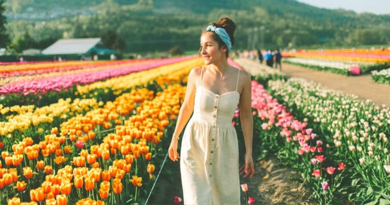 Happy woman in a tulip flower field | Overcome Solo Travel Anxiety