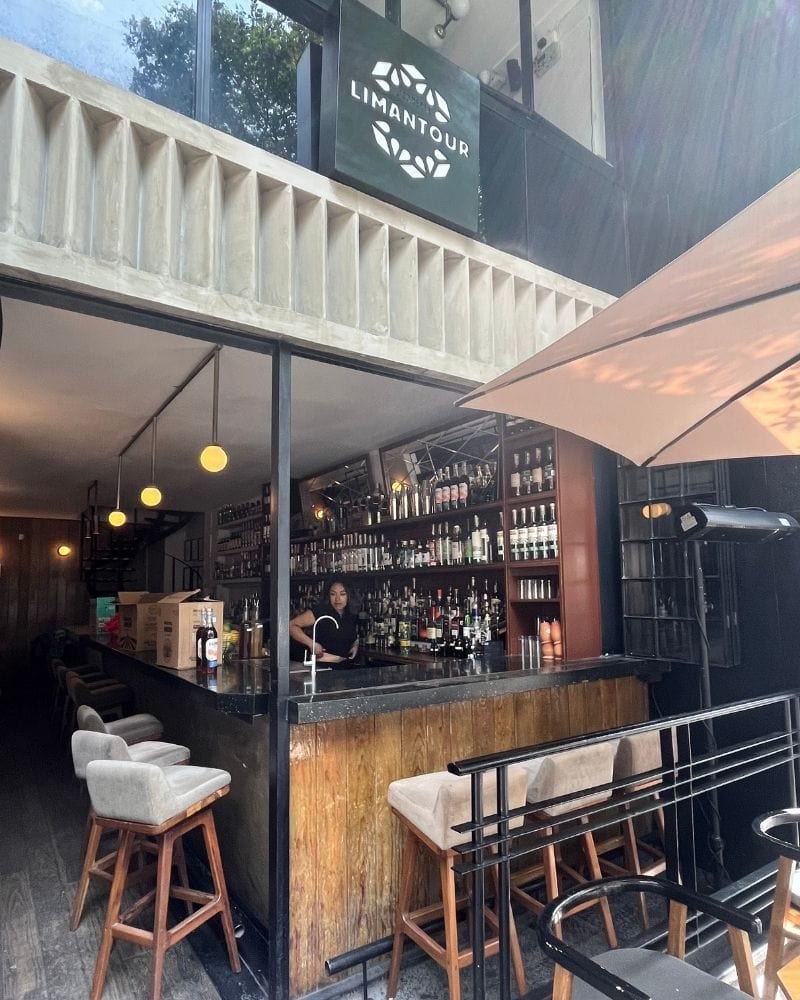 Open-front bar with stools and backlit bottle shelves at Licorería Limantour in Mexico City