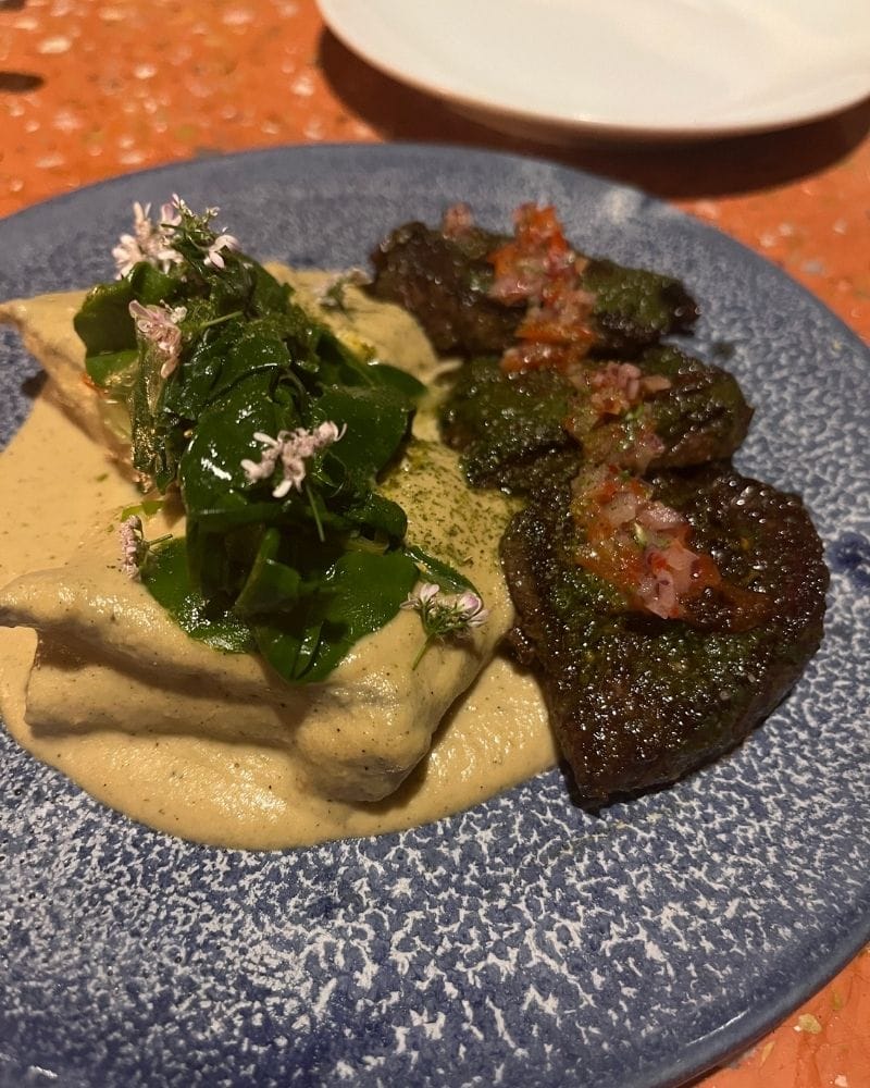 Plated dish with greens, edible flowers and a creamy sauce at Esquina Común in Mexico City