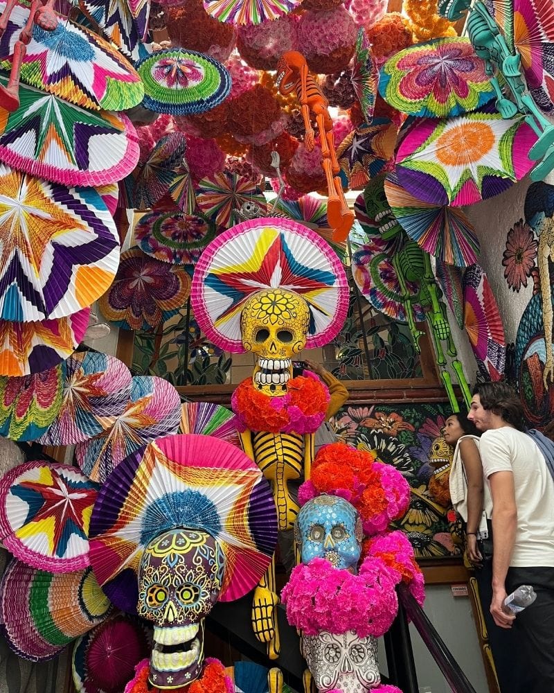 Paper fans, sugar skulls and flower-crowned skeletons at a Coyoacán festival stand in Mexico City for Day of the Dead