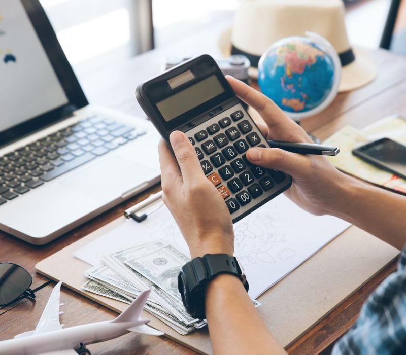 man holding a calculator and budgeting for summer trip