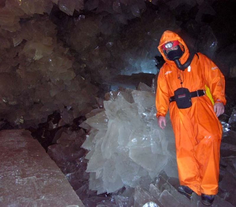 man wearing orange suit posing next to large crystals