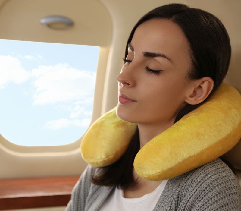 sleeping woman on a flight using a yellow neck pillow