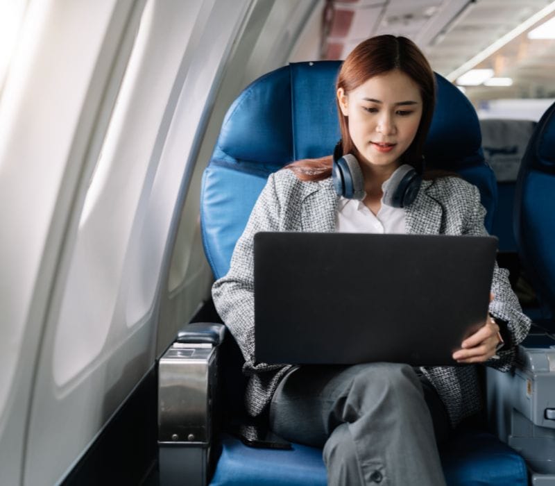 woman using laptop on the plane and wearing headphones