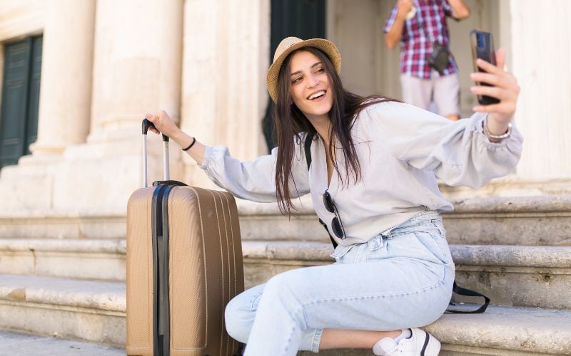 woman holding a brpwn luggage video calling friends