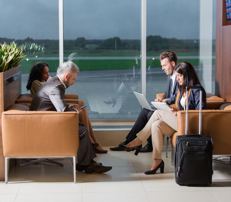 four people sitting in brown lounging seats in airport's lounging area