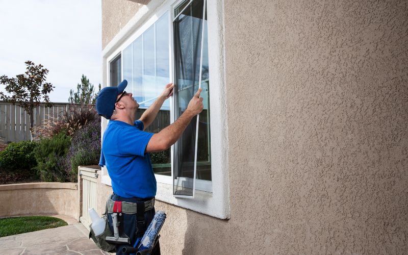 man in blue uniform installing window screen