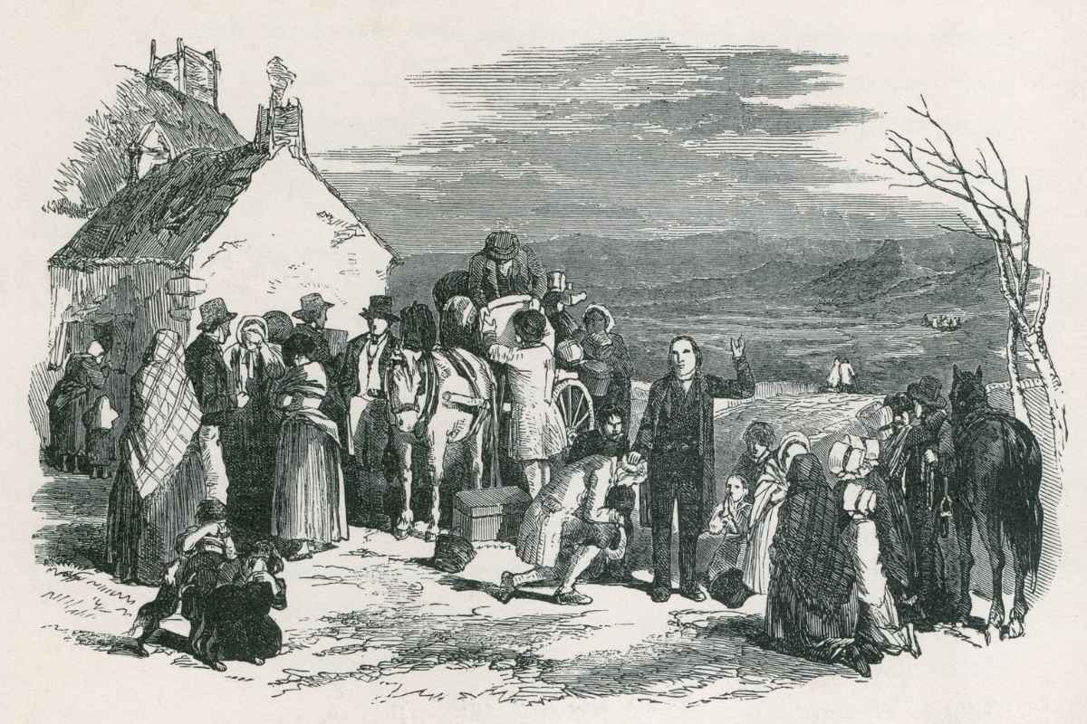 A Catholic priest blesses kneeling immigrants as they to leave their homes and families in Ireland for North America during the potato famine. Ca. 1850.