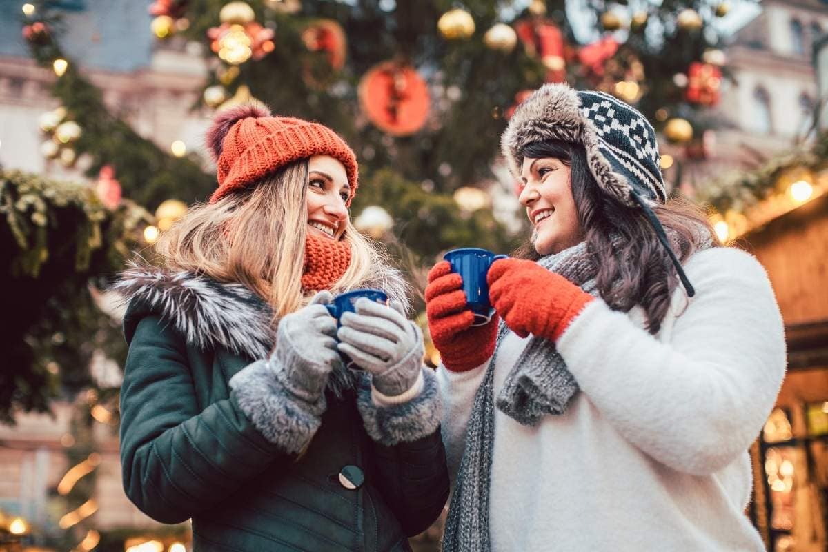 Two women drinking a cup of hot chocolate, Christmas Markets in the U.S.