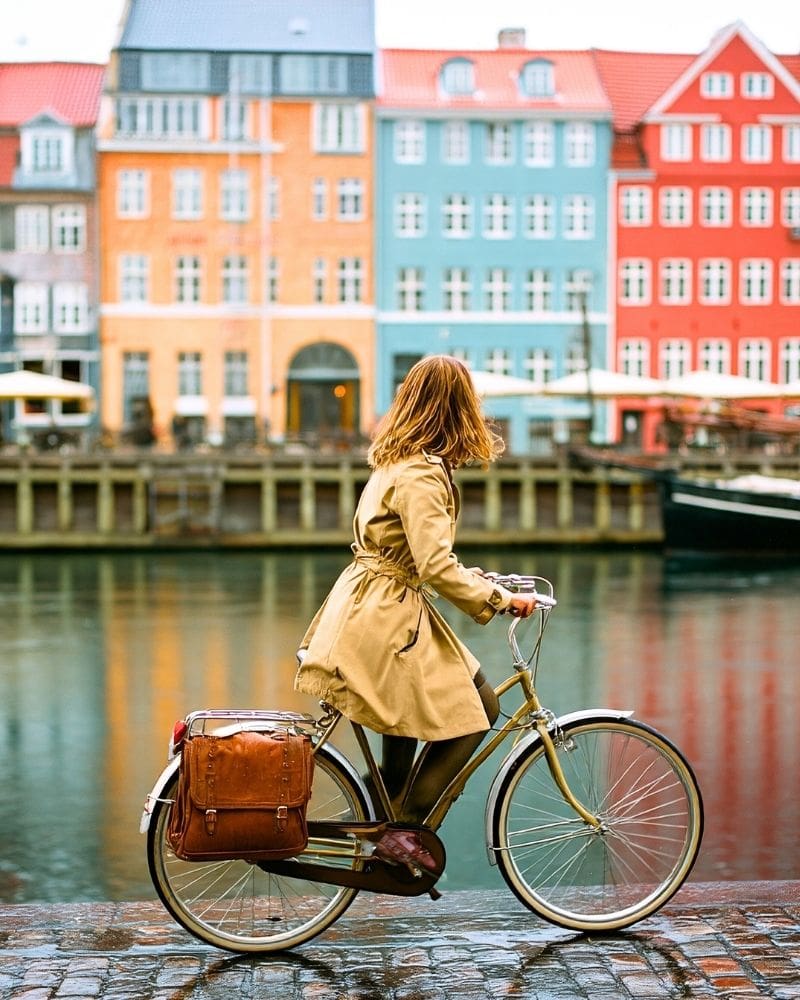 woman riding bike along canal in Copenhagen, Denmark