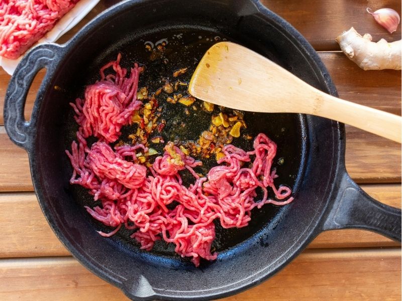 person cooking in a cast iron pan