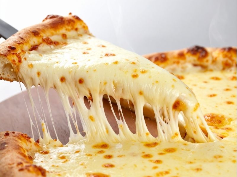 someone taking a slice of cheese pizza from a whole pie