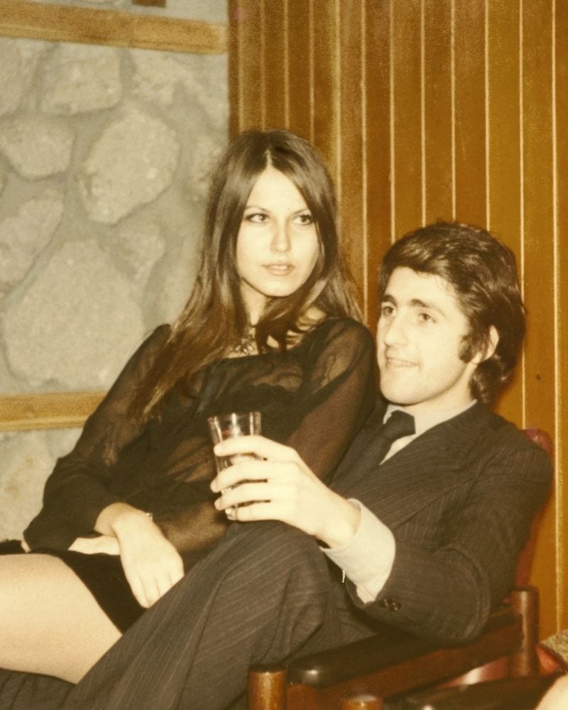 couple sitting near a wall with wood paneling
