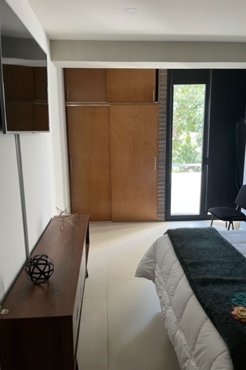 Bedroom with a wood closet and balcony door at the Apartment Near Reforma in Tabacalera, Mexico City