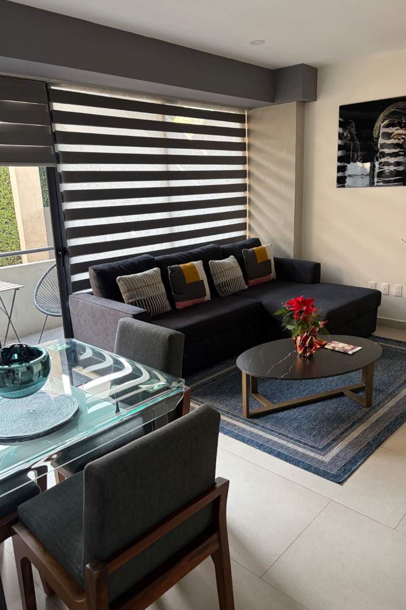 Living room with a dark sofa and glass dining table at the Apartment Near Reforma and the Historic Center in Tabacalera, Mexico City