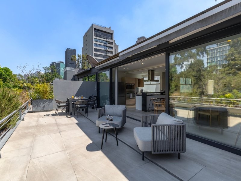 Sunny private terrace with lounge chairs overlooking the trees at the Capitalia Apartment in Polanco, Mexico City