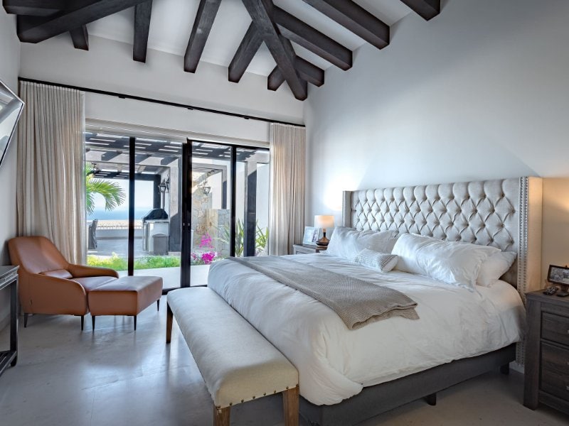 Bedroom with beamed ceilings and glass doors to the patio at Casa Alvar in Quivira, Cabo San Lucas