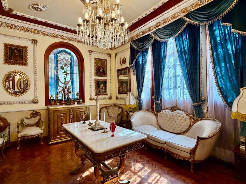 Ornate salon with a crystal chandelier and antique furniture at Casa de las Campanas, a 1904 palace in Roma Norte, Mexico City