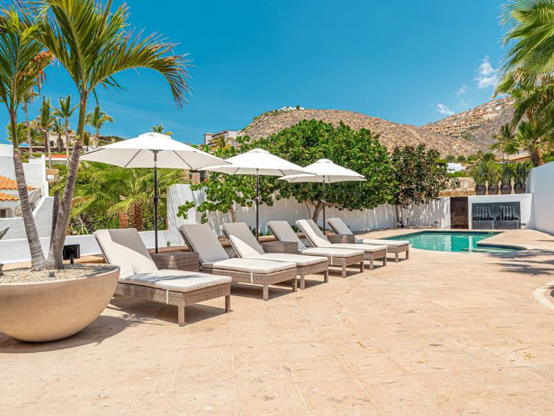 Pool deck with lounge chairs and umbrellas at the 4-Bedroom Pedregal Villa Steps from the Beach in Cabo San Lucas