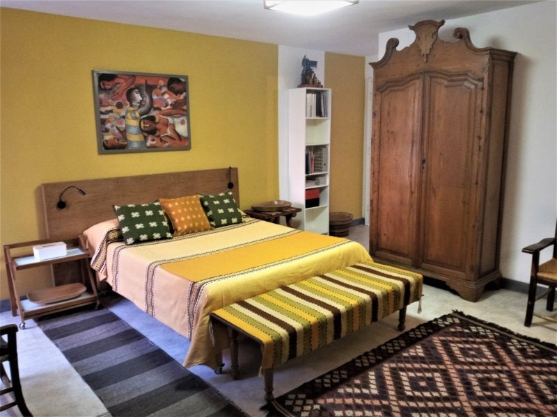 Bed with a striped blanket and antique wardrobe in the Garden Suite in San Miguel Chapultepec, a budget Airbnb in Mexico City