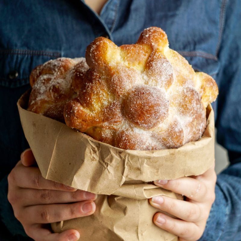 woman holding a pan de muerto (day of the dead bread)