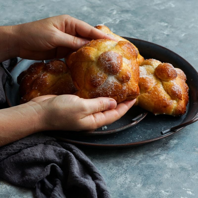 woman holding pan de muerto (day of the dead bread)