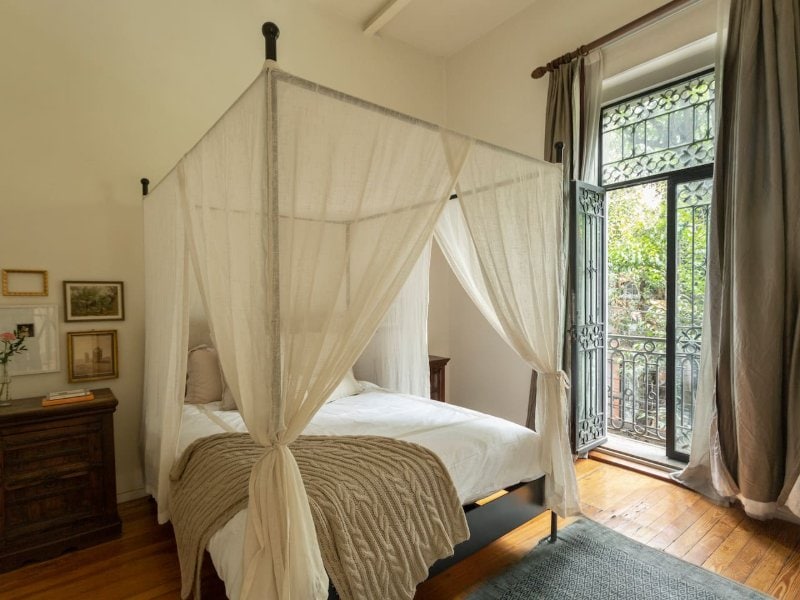 Canopy bed by the balcony doors at the vintage 1900s home Airbnb in Roma Norte, Mexico City