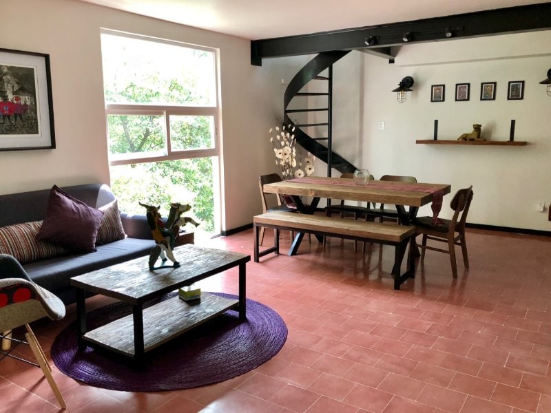 Living and dining room with a spiral staircase at La Conchita Buhardilla Airbnb in Coyoacán, Mexico City