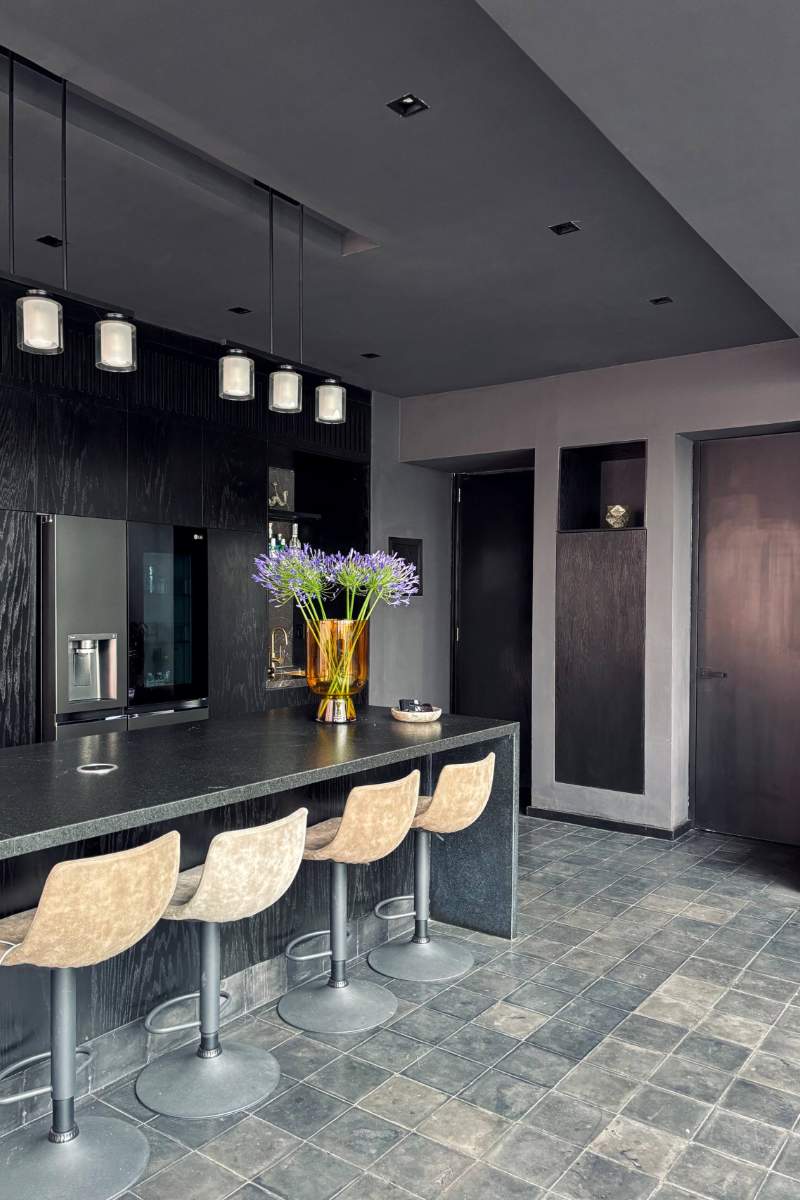 Black kitchen with a breakfast bar and pendant lights at Lavish in Black, a 2-story apartment in Condesa, Mexico City