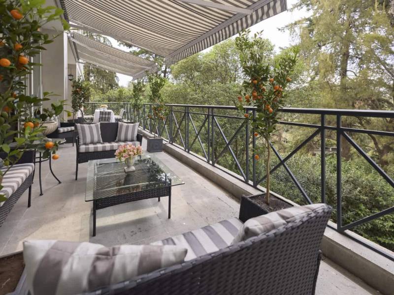 Covered terrace with sofas surrounded by trees at the Luxury Villa in Lomas Altas, Mexico City