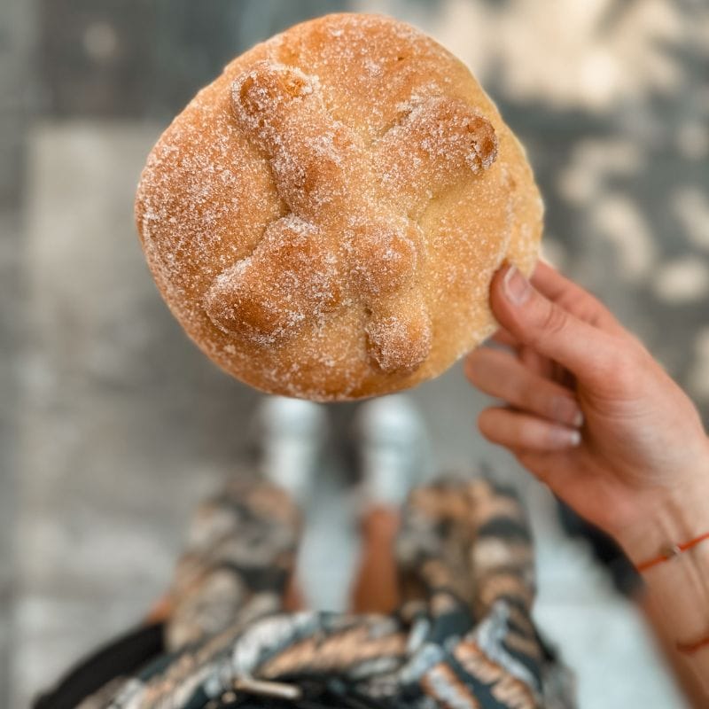woman holding pan de muerto (day of the dead bread)