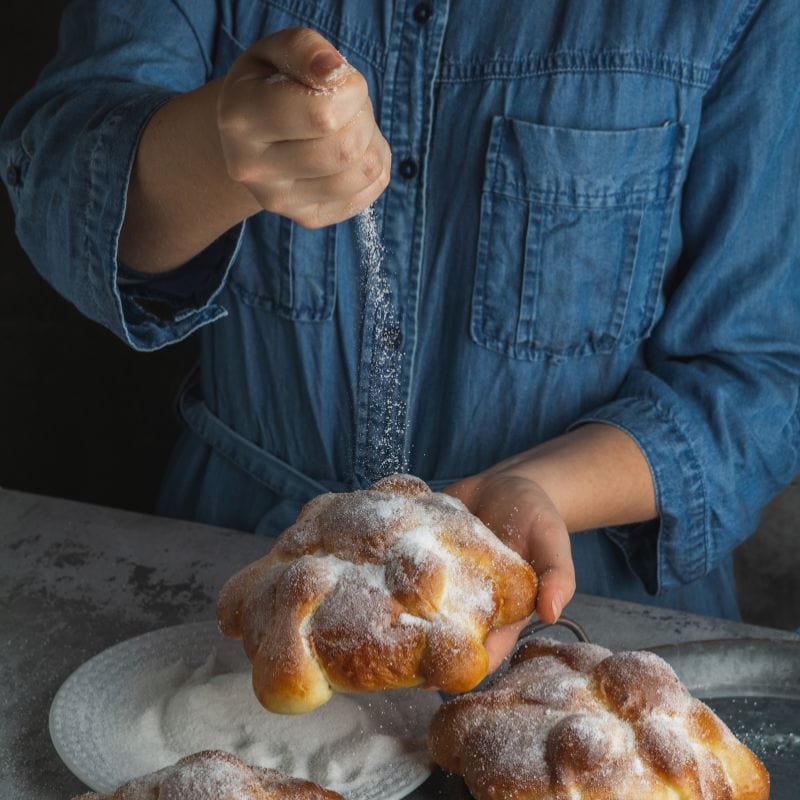 putting sugar on pan de muerto