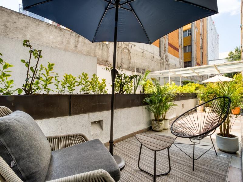 Private patio with plants and an umbrella at a Roma Norte Mexico City Airbnb