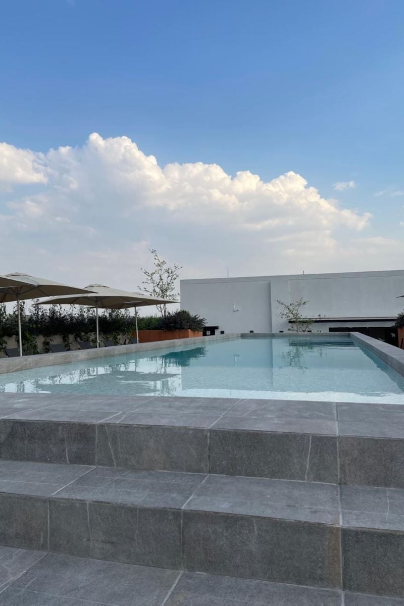 Rooftop building pool under blue skies at the Roma Suite with a Building Pool, a budget Airbnb in Mexico City's Roma Norte