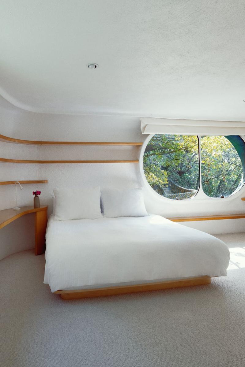 Main bedroom with curved built-in shelves and an oval window at the Mexico City snake house
