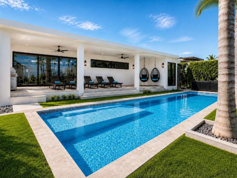 Lap pool and covered patio with hanging chairs at Villa Utopia in Cabo San Lucas