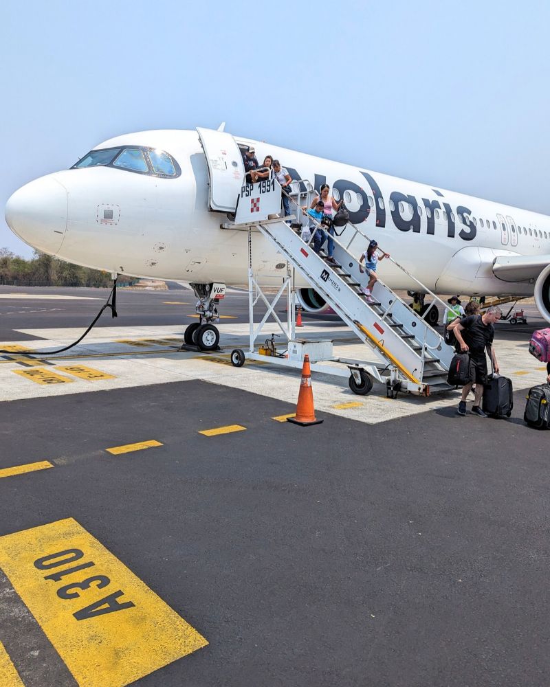 passengers walking down the stairs from a volaris plane on the tarmac